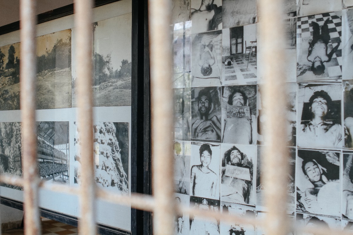 Tuel Sleng Genocide Museum. Black and white pictures of people that perished in the genocide hang on a wall behind metal bars.  