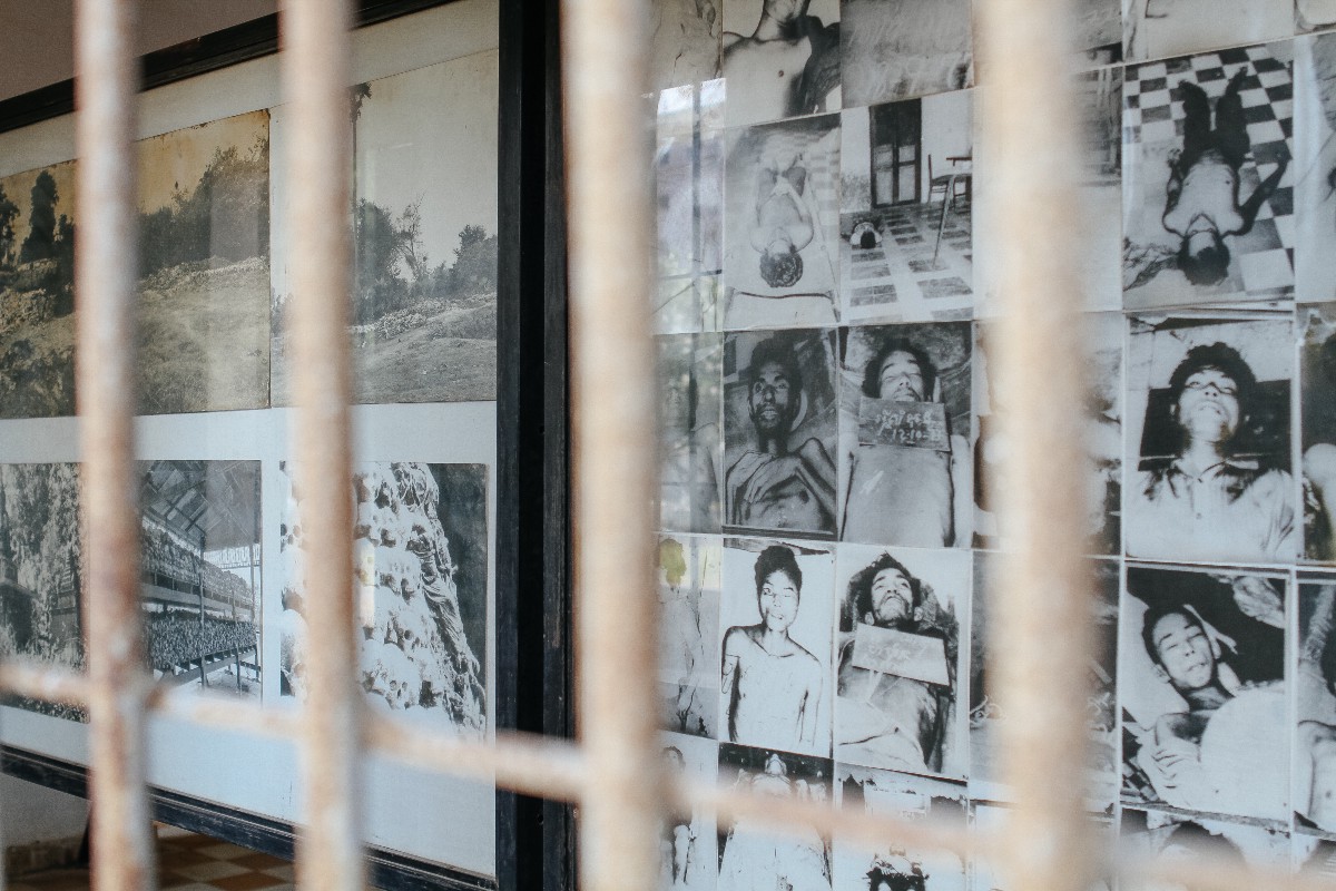 Tuel Sleng Genocide Museum. Black and white pictures of people that perished in the genocide hang on a wall behind metal bars.