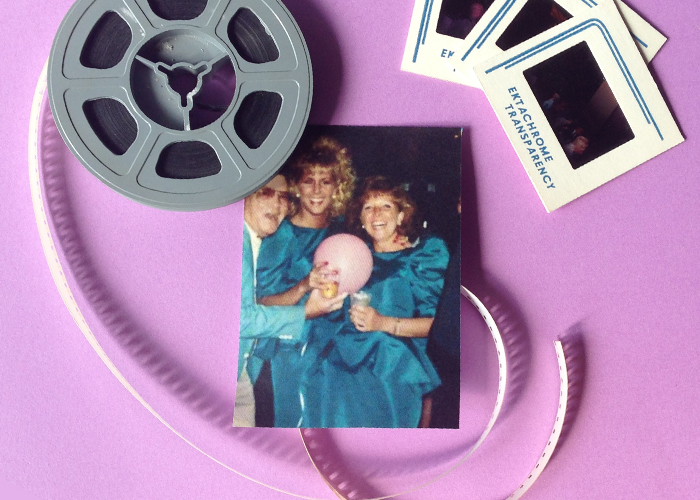 In the middle of the frame sits an old prom photo from the 80s. It's of three friends -- a male wearing a blue suit coat, a blonde woman with curly permed hair and a blue satin dress, and a brunette wearing a blue dress with large gathered shoulder pads. On tope of the photo sits a film reel, some of its film snakes around and sits under the images bottom corner. On the top right of the frame are three fanned out slides. Everything sits on a light purple background. 